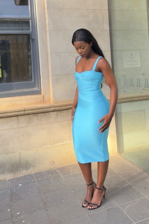 Woman in a light blue dress standing outside a building.